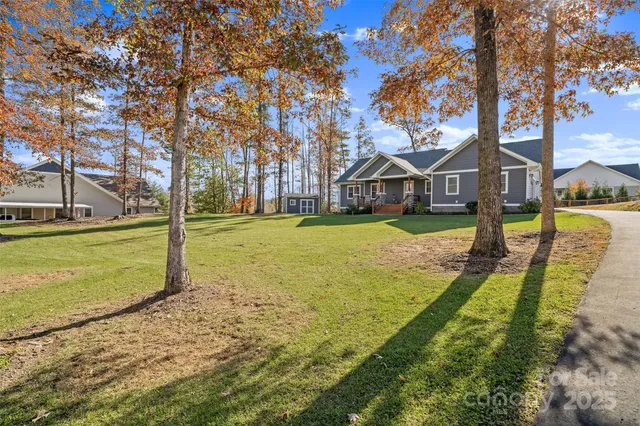 a view of a big yard next to a house with large trees