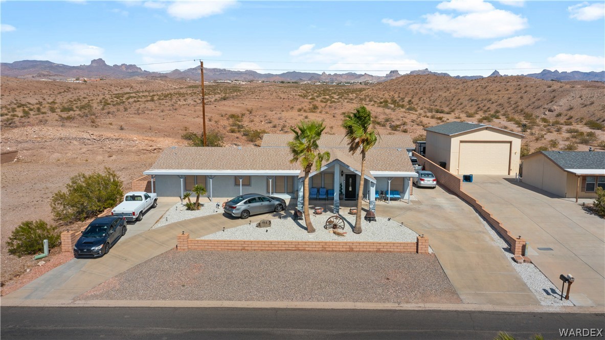 784 Pegasus Ranch Road Bullhead City, AZ 86429 - Photo 88 of 100 Desert landscape surrounding a single-story residence with an attached carport, an additional detached garage, and an extended paved driveway