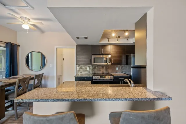 a kitchen with kitchen island granite countertop a sink a stove and a refrigerator