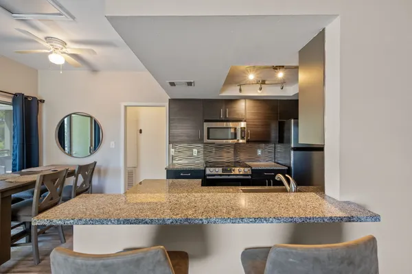 a kitchen with kitchen island granite countertop a sink a stove and a refrigerator