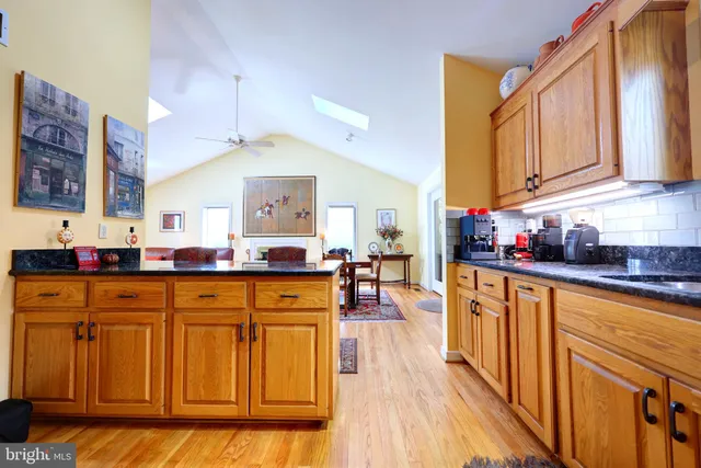 a kitchen with stainless steel appliances granite countertop wooden cabinets a sink and dishwasher a stove with wooden floor