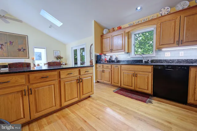a kitchen with stainless steel appliances granite countertop a stove a sink dishwasher and cabinets with wooden floor