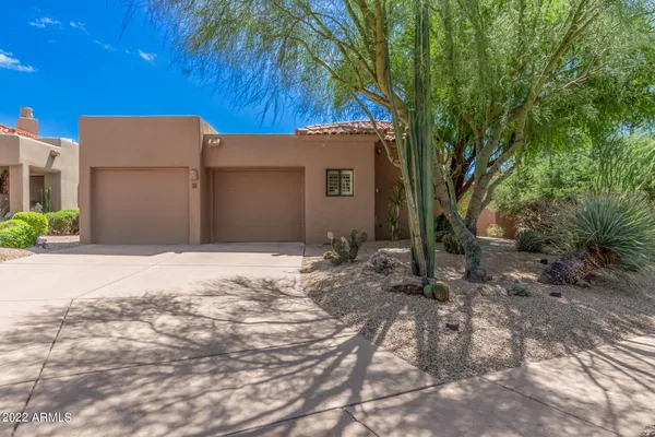 a backyard of a house with large trees and a wooden fence