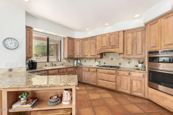 a kitchen with kitchen island granite countertop a stove a sink and white cabinets