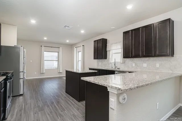a kitchen with granite countertop stainless steel appliances a sink cabinets and wooden floor