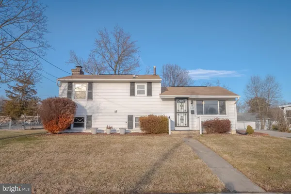a view of a house with a yard and large tree