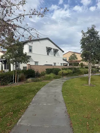 a view of a white house next to a yard with big trees