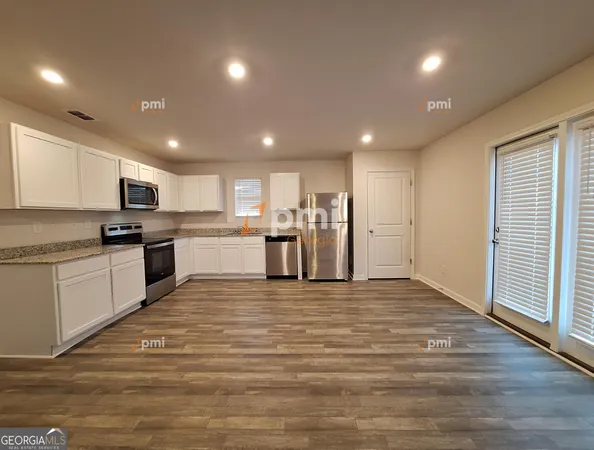 a large white kitchen with wooden floors stainless steel appliances and white cabinets
