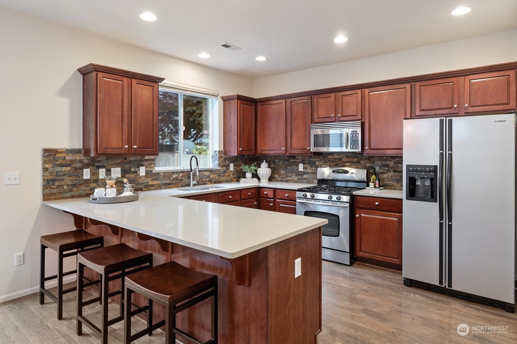 16023 35th Park Southeast Bothell, WA 98012 - Photo 9 of 34 a kitchen with kitchen island granite countertop wooden cabinets a stove a sink and a refrigerator with wooden floor