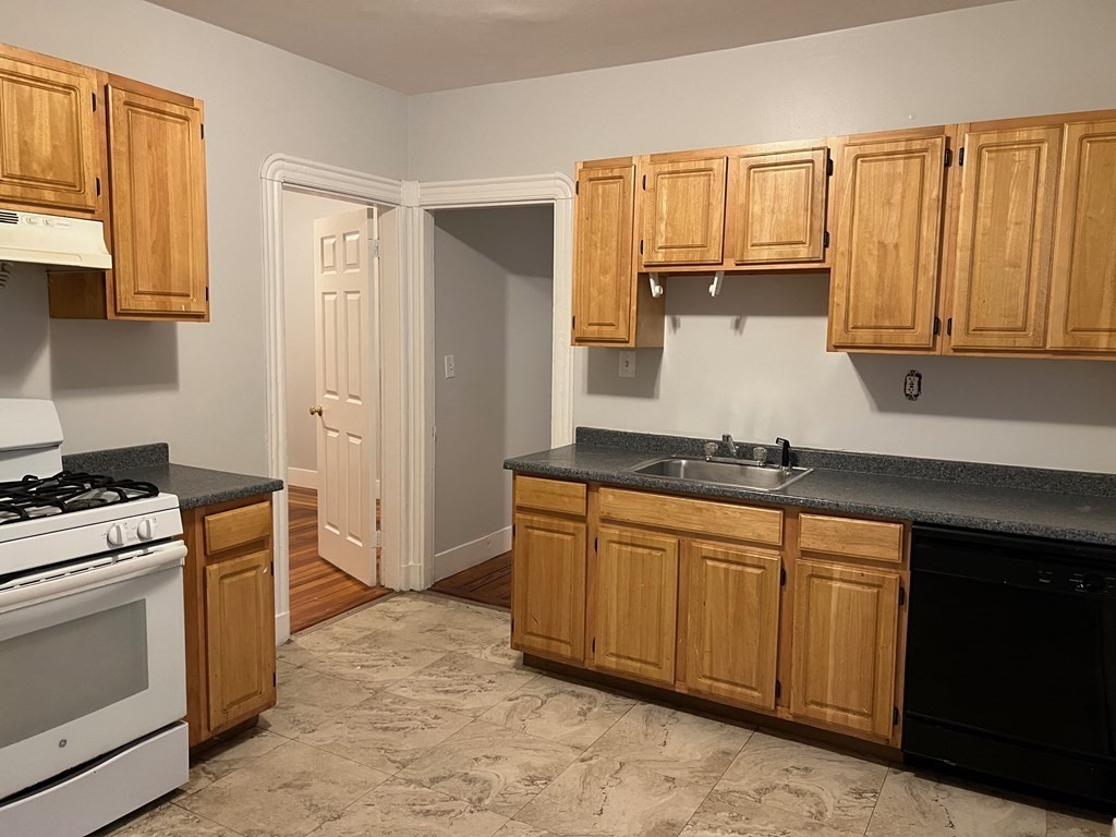 a kitchen with granite countertop a stove sink and cabinets
