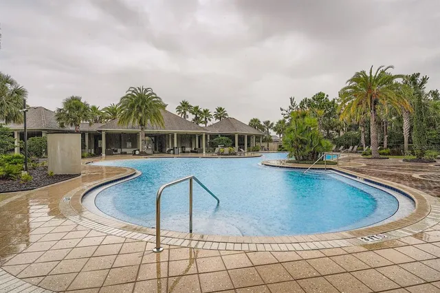 a view of swimming pool with outdoor seating and house in the background