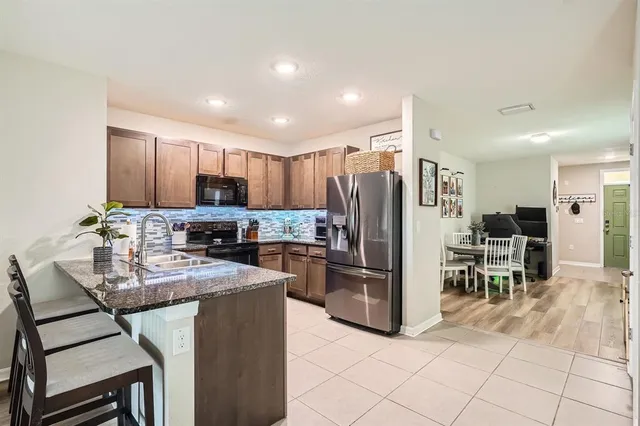 a kitchen with kitchen island granite countertop a refrigerator stove microwave and cabinets