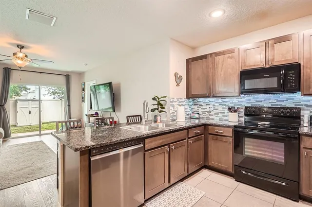a kitchen with stainless steel appliances kitchen island granite countertop a sink stove and microwave
