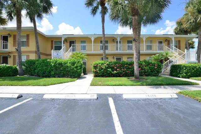 front view of house with a yard and palm trees