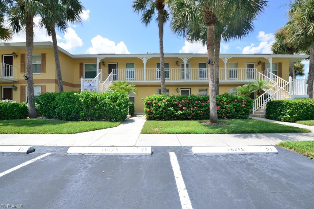 front view of house with a yard and palm trees