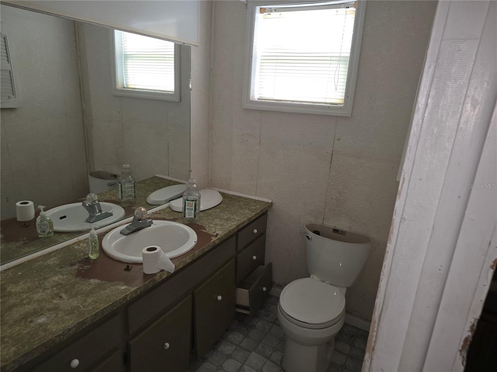 404 Northwest 7th Street Mulberry, FL 33860 - Photo 15 of 22 a bathroom with a granite countertop toilet a mirror and a sink