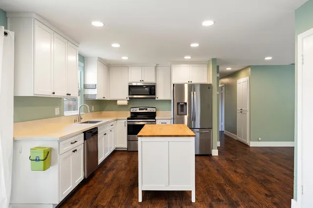 a large kitchen with stainless steel appliances kitchen island a large counter top a stove a sink and a refrigerator