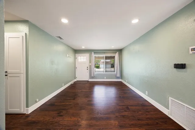 a view of an empty room with wooden floor and a window