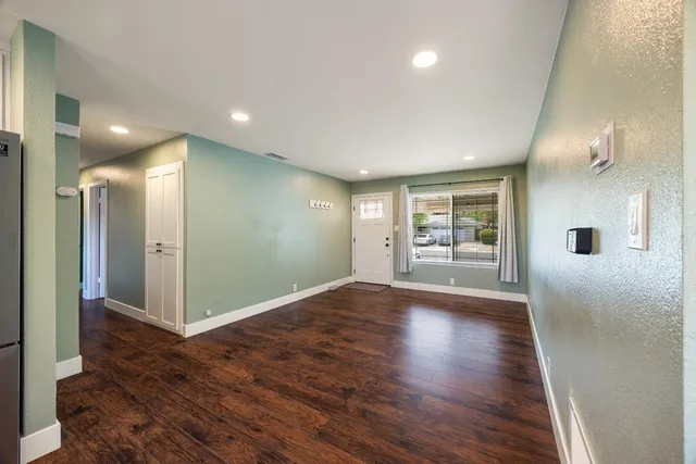 a view of a hallway with wooden floor and a bathroom
