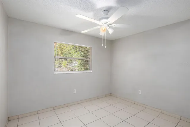 an empty room with windows and chandelier fan