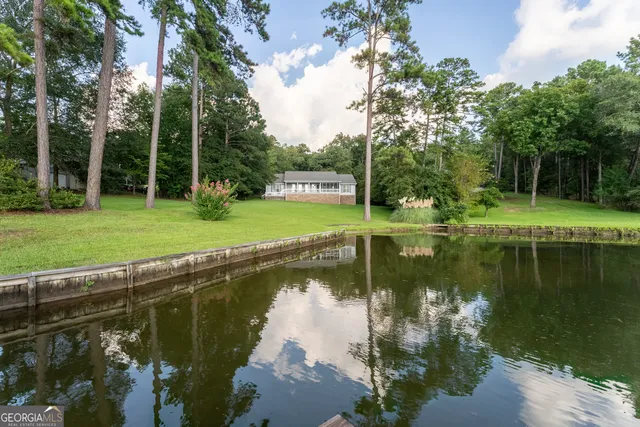a view of a lake with a yard and large trees