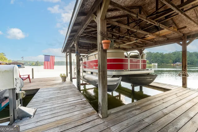 a view of a lake with lawn chairs and large trees