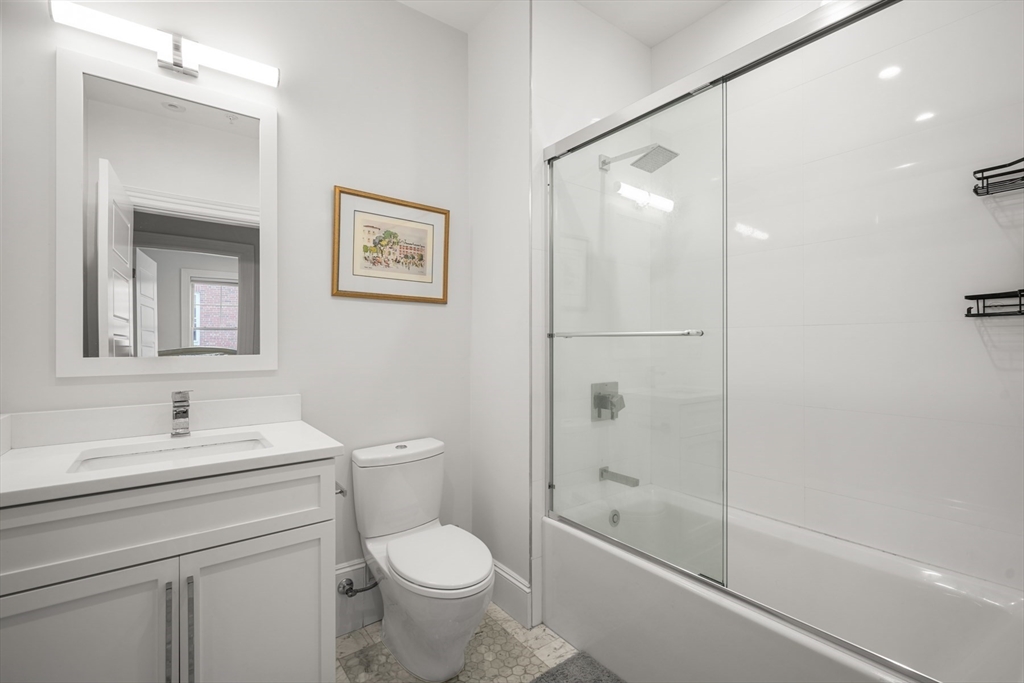 205 E Street, Unit 8N Boston, MA 02127 - Photo 19 of 29 a bathroom with a toilet a sink a mirror a shower and vanity