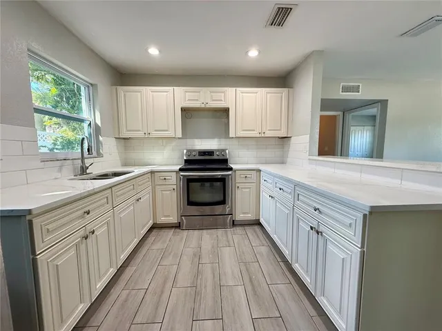 a kitchen with stainless steel appliances hardwood floor sink stove microwave and cabinets