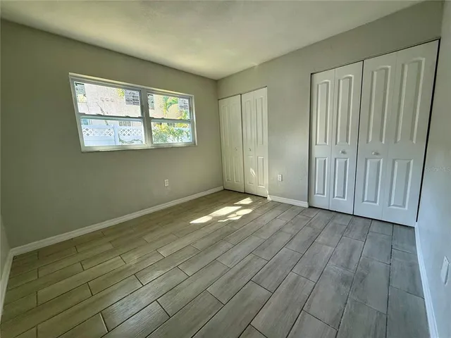 an empty room with wooden floor cabinet and windows