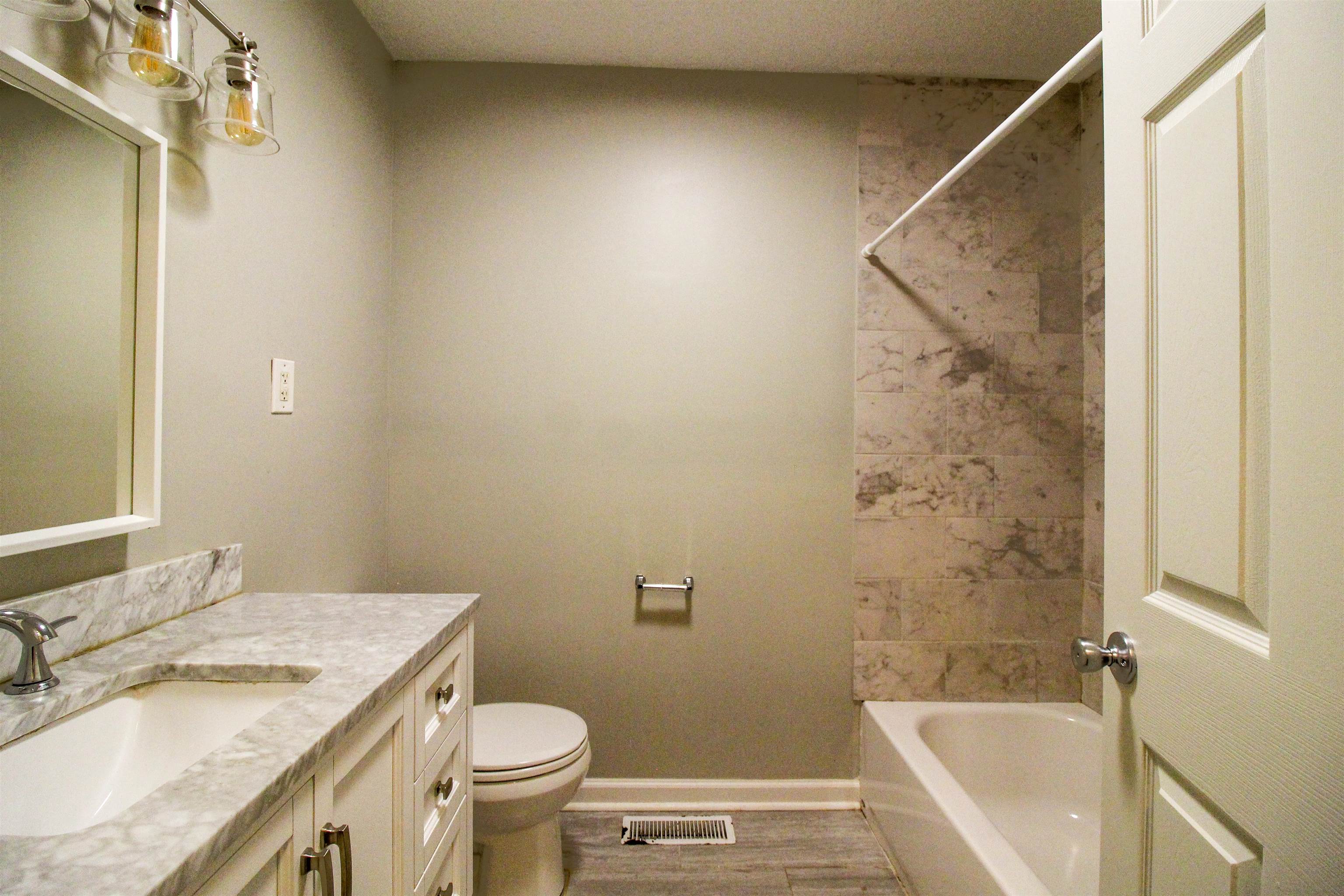 2089 Ralph Road Covington, TN 38019 - Photo 20 of 28 Full bathroom featuring vanity, washtub / shower combination, and light wood-style flooring