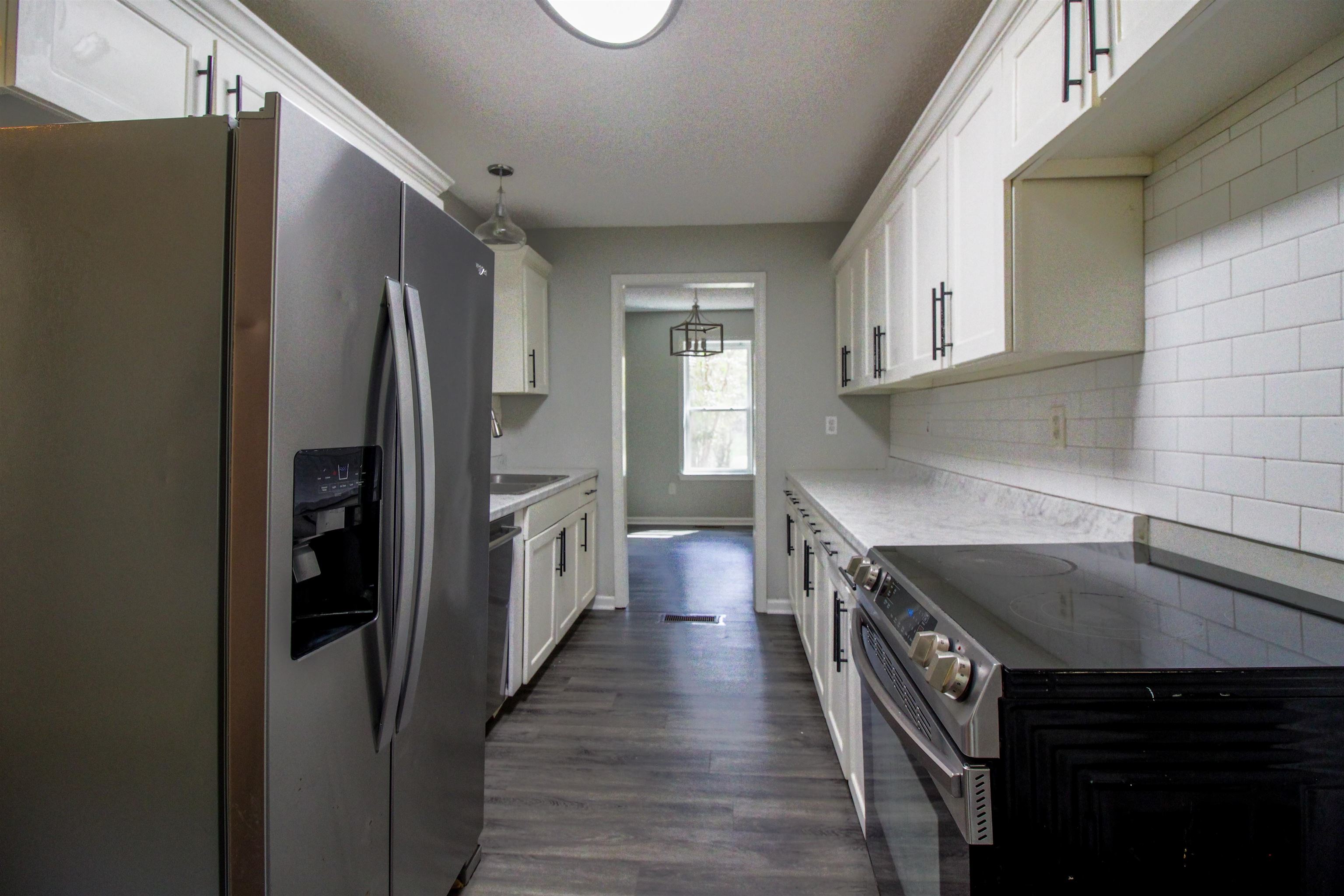 2089 Ralph Road Covington, TN 38019 - Photo 10 of 28 Kitchen featuring stainless steel appliances, white cabinets, dark wood-type flooring, pendant lighting, and backsplash