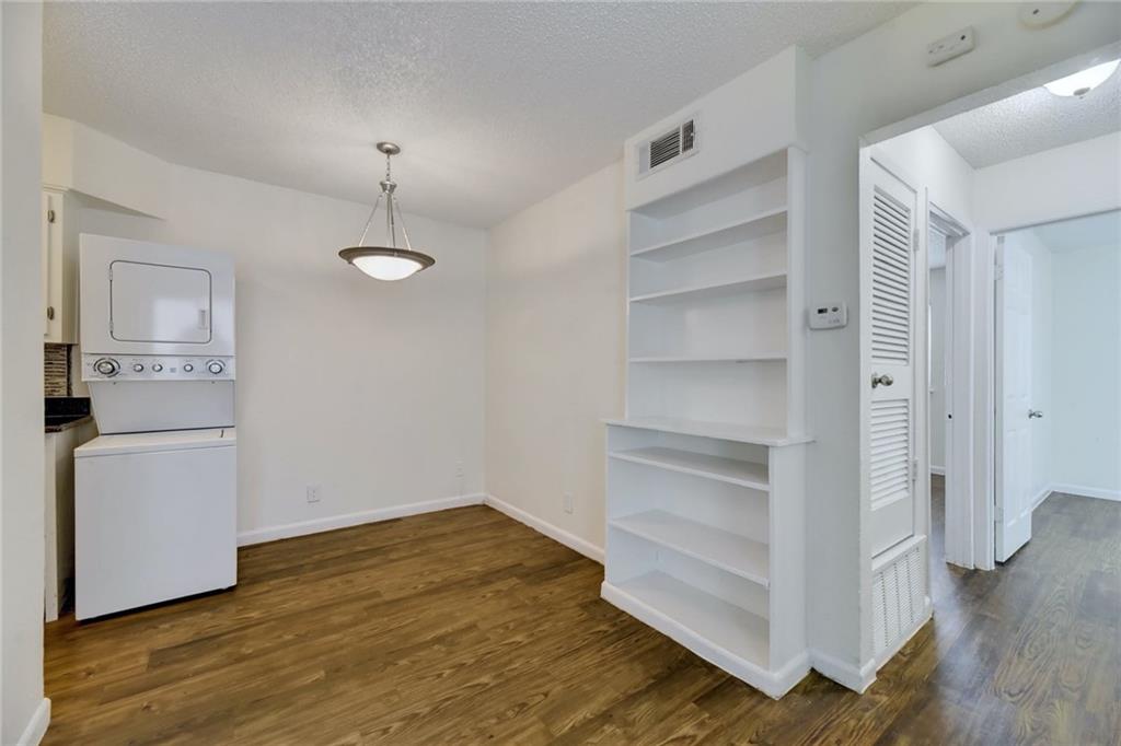 2401 Manor Road, Unit 221 Austin, TX 78722 - Photo 3 of 21 Functional living area featuring a stacked washer and dryer, along with practical built-in shelving.