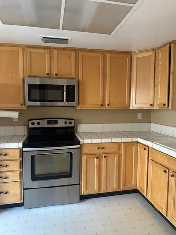 a kitchen with granite countertop a stove top oven microwave and cabinets
