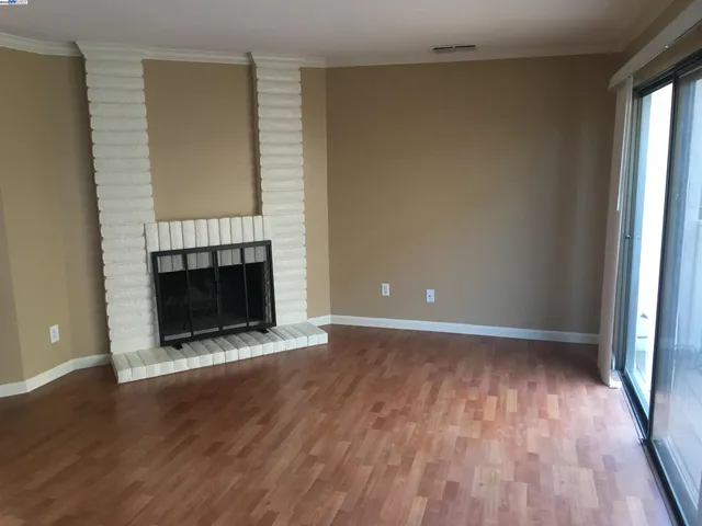 an empty room with wooden floor fireplace and windows