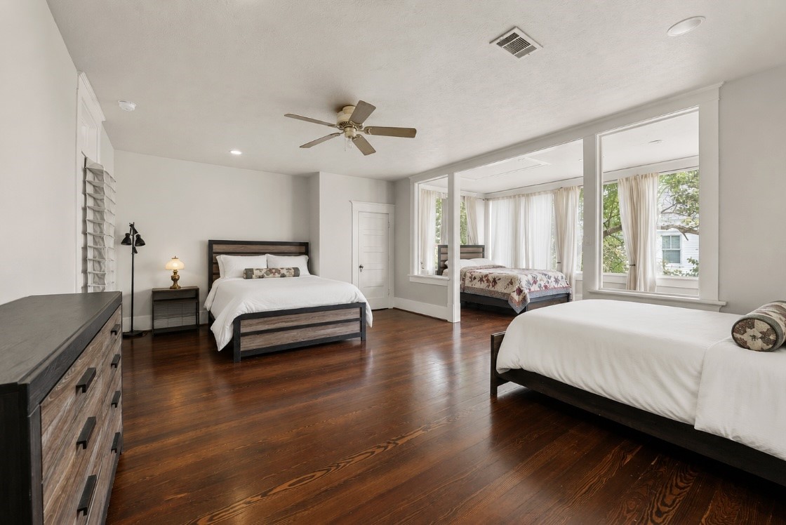 945 Harvard Street Houston, TX 77008 - Photo 22 of 47 This spacious upstairs bedroom boasts a charming sunroom with stunning views of the beautifully landscaped yard and pool, offering a perfect blend of luxury and tranquility.