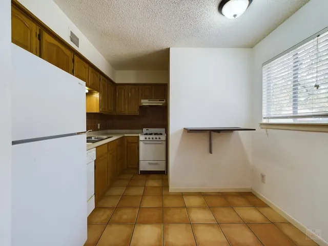 a kitchen with a refrigerator a stove top oven and cabinets