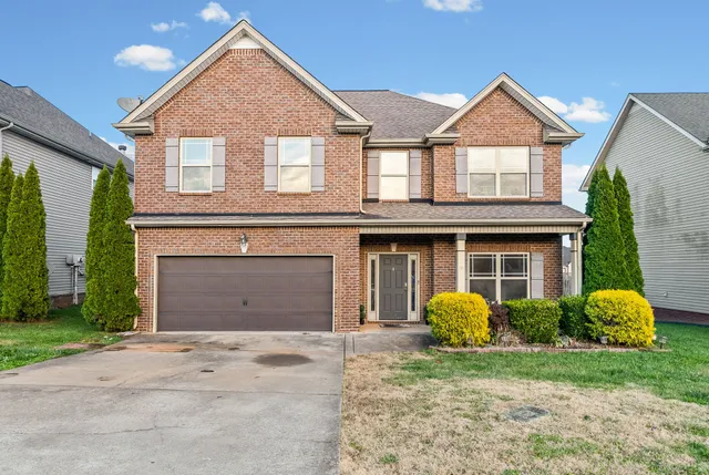 a front view of a house with garden and trees
