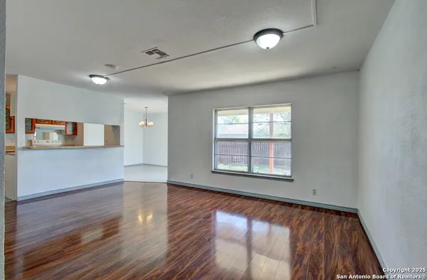 a view of an empty room with wooden floor and a window