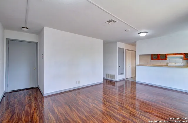 a view of empty room with wooden floor