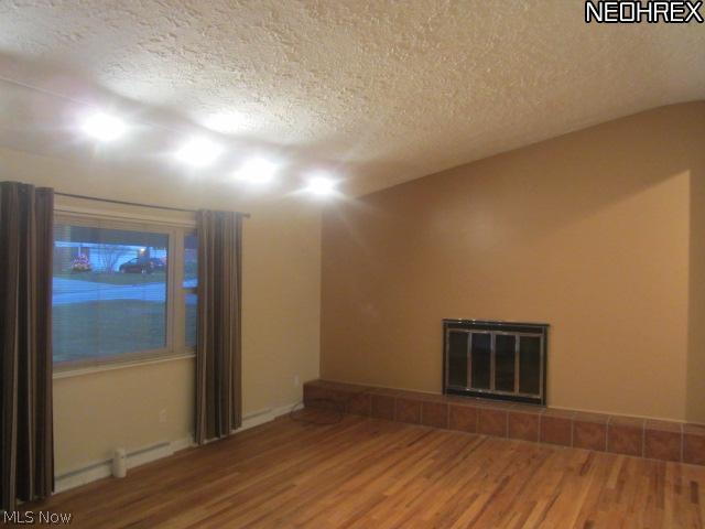 Living room with vaulted ceiling, hard wood floor & wood burning fireplace.