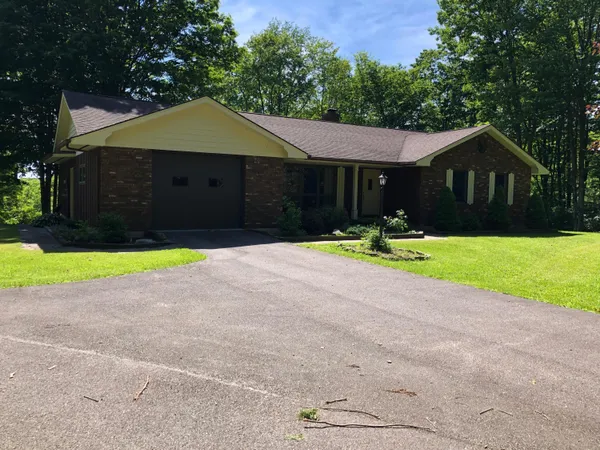 a front view of house with yard and trees in the background