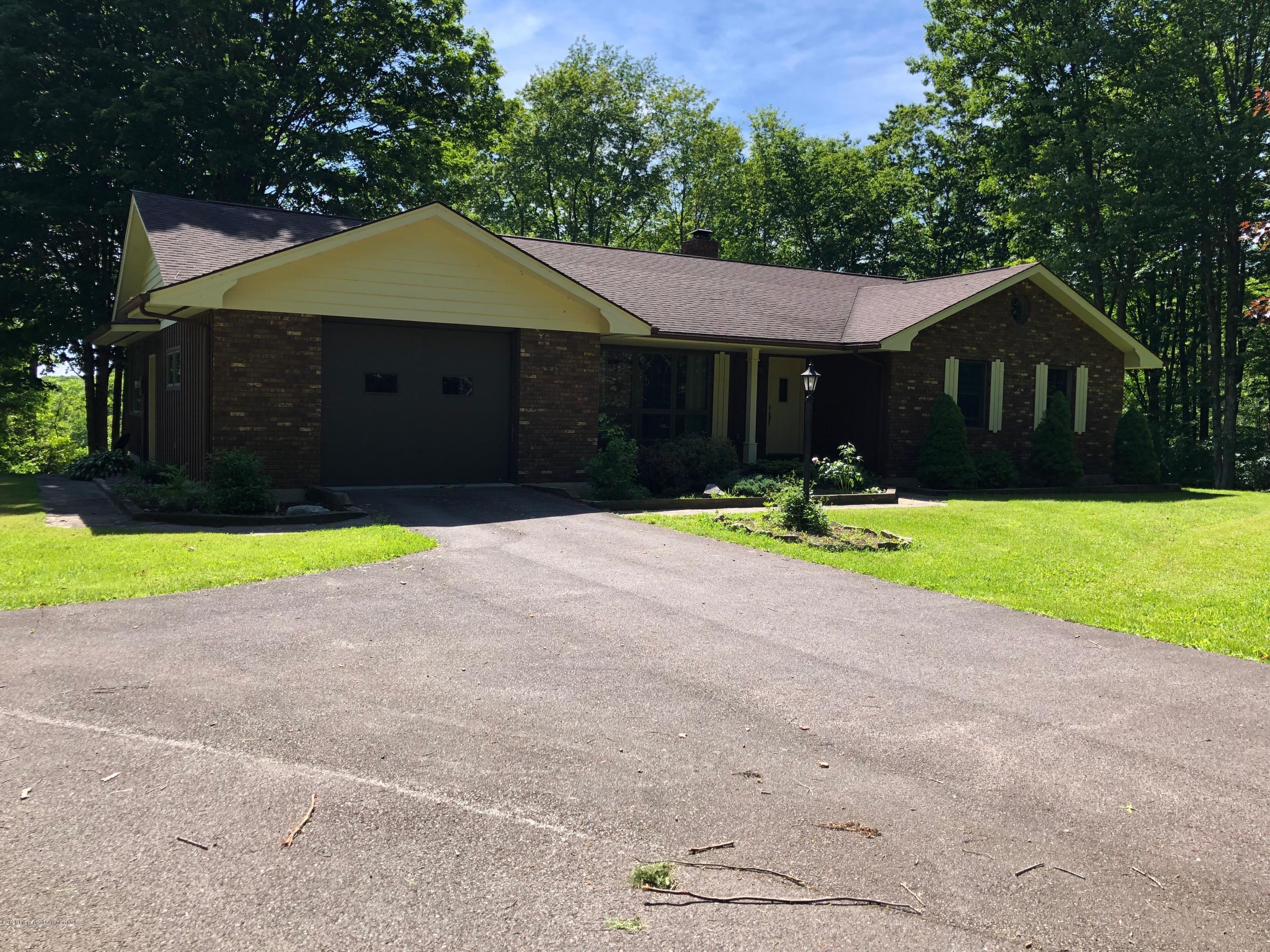 a front view of house with yard and trees in the background