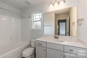 a bathroom with a toilet a sink a mirror a bathtub and vanity