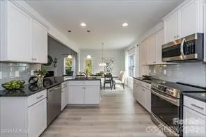 a kitchen with stainless steel appliances kitchen island granite countertop a sink a stove top oven a counter space and cabinets