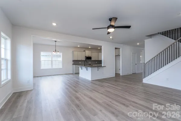 an empty room with wooden floor kitchen view and a window
