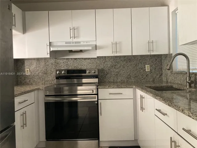 a kitchen with granite countertop white cabinets and white appliances
