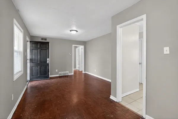 an empty room with wooden floor and windows
