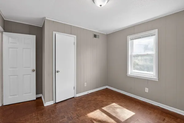 a view of an empty room with wooden floor and a window