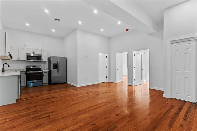 a view of kitchen with stainless steel appliances wooden floor and large window