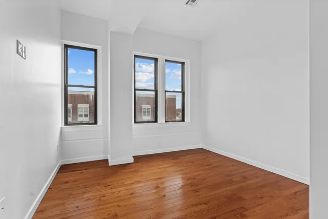 a view of an empty room with wooden floor and windows